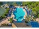 Aerial view of a large outdoor swimming pool with lounge chairs and umbrellas surrounded by palm trees at 141 Bella Vista Ter # 34D, Nokomis, FL 34275