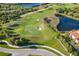 Aerial view of golf course featuring lush green grass, sand traps, and a nearby lake at 141 Bella Vista Ter # 34D, Nokomis, FL 34275