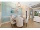 Elegant dining room with a modern light fixture, a large beach painting, and a table set for six at 141 Bella Vista Ter # 34D, Nokomis, FL 34275