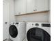 Laundry room with white washer and dryer and white cabinets above at 1617 Sea Haven Dr # 502, Punta Gorda, FL 33950