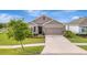 Inviting home with a spacious driveway, well-kept lawn, and mature tree providing shade and character at 16341 Little Garden Dr, Wimauma, FL 33598