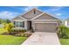 Well-maintained home with a two-car garage, verdant lawn, and thoughtfully designed landscaping for a welcoming feel at 16341 Little Garden Dr, Wimauma, FL 33598