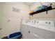 Bright laundry room features a washer, dryer, storage shelf, and cute decor at 16341 Little Garden Dr, Wimauma, FL 33598