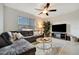 Cozy living room featuring a large sectional sofa, neutral rug and a ceiling fan at 16341 Little Garden Dr, Wimauma, FL 33598