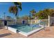 Community hot tub with brick paver patio and white picket fence surrounded by lush tropical foliage and blue skies at 1712 Starling Dr # 101, Sarasota, FL 34231