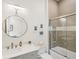 Well-lit bathroom featuring a vanity with a round mirror and a glass-enclosed tub/shower at 17820 Waterville Pl, Lakewood Ranch, FL 34202