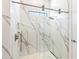 Elegant primary bathroom with a glass shower featuring beautiful marble tile and modern fixtures at 17820 Waterville Pl, Lakewood Ranch, FL 34202