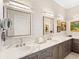 Bathroom featuring double sinks with cabinets and decorative mirrors and sconces at 17820 Waterville Pl, Lakewood Ranch, FL 34202