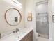 Stylish bathroom featuring a modern vanity with a round mirror and a glass-enclosed shower at 17820 Waterville Pl, Lakewood Ranch, FL 34202