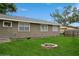 A spacious backyard with lush green lawn and a charming fire pit area with gray house in background at 1813 5Th W St, Palmetto, FL 34221