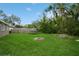 A spacious backyard with lush green lawn, mature trees, a trampoline, and a fire pit at 1813 5Th W St, Palmetto, FL 34221