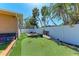 Backyard with artificial grass, privacy fence, and tropical landscaping at 216 Archer Way, Anna Maria, FL 34216