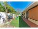 Sprawling backyard with artificial grass, mature landscaping, and a privacy fence at 216 Archer Way, Anna Maria, FL 34216