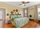 Sunny bedroom with a queen bed, ceiling fan, hardwood floors, and decorative hats on the wall at 2326 2Nd E Ave, Bradenton, FL 34208