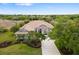 Aerial view of a tan single-story home featuring a tile roof, lush landscaping, and a long driveway in a wooded neighborhood at 244 Dove Trl, Bradenton, FL 34212