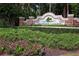 Community entrance sign amidst lush greenery, with pink flowers adding a pop of color at 244 Dove Trl, Bradenton, FL 34212