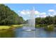 Scenic water fountain surrounded by lush greenery and a serene pond landscape under a bright blue, partly cloudy sky at 244 Dove Trl, Bradenton, FL 34212