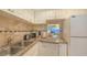 Bright white kitchen with granite countertop, white appliances and peek-a-boo pass through window at 4350 Chatham Dr # E-105, Longboat Key, FL 34228