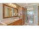 Bathroom with double sink vanity, large mirror, wood cabinets, and a glass enclosed shower at 464 Golden Gate Pt # 702, Sarasota, FL 34236
