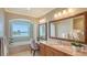 Bright bathroom with double sink, large framed mirrors, tub under window with a bay view at 464 Golden Gate Pt # 702, Sarasota, FL 34236