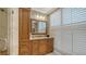 Bright bathroom with natural wood cabinets, marble countertops, a large mirror and white shutters at 464 Golden Gate Pt # 702, Sarasota, FL 34236