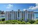 Elegant condominium exterior featuring multi-story balconies and lush landscaping under a bright blue sky at 464 Golden Gate Pt # 702, Sarasota, FL 34236