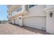 Exterior view of multi-car garage doors with brick paved driveway in front of a white condo building at 464 Golden Gate Pt # 702, Sarasota, FL 34236