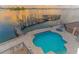 Aerial view of a private pool and pier overlooking a calm bay and a golden horizon at 464 Golden Gate Pt # 702, Sarasota, FL 34236