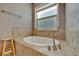 Bathroom with tiled bathtub, tiled deck, wooden stool and a window for natural lighting at 5009 Lake Overlook Ave, Bradenton, FL 34208