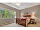 Relaxing main bedroom with a large window showing a lush landscape view and a tray ceiling with fan at 5009 Lake Overlook Ave, Bradenton, FL 34208