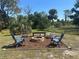 Outdoor fire pit with Adirondack chairs and rustic bench creates cozy gathering space at 534 Lewis St, Englewood, FL 34223