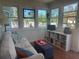 Bright sunroom with a white couch, bookshelf, and multiple windows providing ample natural light at 534 Lewis St, Englewood, FL 34223