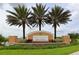 Welcoming entrance sign to Harmony at Lakewood Ranch with vibrant landscaping and palm trees at 5520 Coachwood Cv, Bradenton, FL 34211