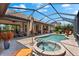 View of a screened-in pool and spa with an umbrella, lounge chairs and an outdoor kitchen at 5637 Arnie Loop, Bradenton, FL 34211