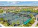 Aerial view of meticulously maintained tennis courts surrounded by palm trees and lush landscaping in a gated community at 5637 Arnie Loop, Bradenton, FL 34211