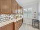 Kitchen dry bar area with wood cabinets, light countertops, tiled backsplash, wine fridge, and window with plantation shutters at 6228 Champions Row St, Bradenton, FL 34210