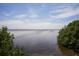 Expansive view of calm water with green foliage on the sides beneath clear skies and sparse clouds at 6228 Champions Row St, Bradenton, FL 34210