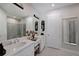 Bright bathroom with double sinks, a large mirror, white cabinetry, and a glass-enclosed shower at 6308 Plateau Ct, Bradenton, FL 34203