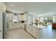 Modern kitchen with stainless steel appliances, white cabinets, and a view into the bright and open living room at 6308 Plateau Ct, Bradenton, FL 34203