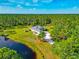 Aerial view showcasing home's expansive lot with mature trees, pond, and circular driveway at 6407 213Th E St, Bradenton, FL 34211