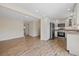 An open-concept kitchen and living room area featuring wood floors, white cabinets, and stainless steel appliances at 6718 68Th E Ave, Bradenton, FL 34203