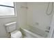 Bathroom with a white tiled tub and shower, modern toilet, and small window at 7173 W Country Club N Dr # 141, Sarasota, FL 34243