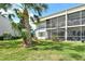 Condo building exterior with a grass lawn and tropical landscaping at 7173 W Country Club N Dr # 141, Sarasota, FL 34243