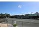 Tennis court with players at Palm-Aire Racquet Club, surrounded by fencing and trees, under a sunny sky at 7173 W Country Club N Dr # 141, Sarasota, FL 34243