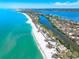 Expansive aerial view features coastal homes nestled along a shore next to clear, turquoise waters at 8592 Hidden Lagoon Rd, Sarasota, FL 34242
