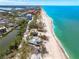Stunning coastal aerial view of a home nestled on a white sandy beach next to turquoise waters at 8592 Hidden Lagoon Rd, Sarasota, FL 34242