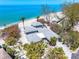 An aerial view of a beautiful beach home surrounded by palm trees and turquoise waters at 8592 Hidden Lagoon Rd, Sarasota, FL 34242