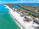 Coastal view from above showcases the beach homes nestled along a shoreline next to clear, turquoise waters at 8592 Hidden Lagoon Rd, Sarasota, FL 34242