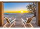 Stunning sunset view from beachside home with two chairs on the porch overlooking the ocean at 8592 Hidden Lagoon Rd, Sarasota, FL 34242