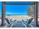 Covered porch overlooking a white sand beach and blue ocean, with two Adirondack chairs at 8592 Hidden Lagoon Rd, Sarasota, FL 34242